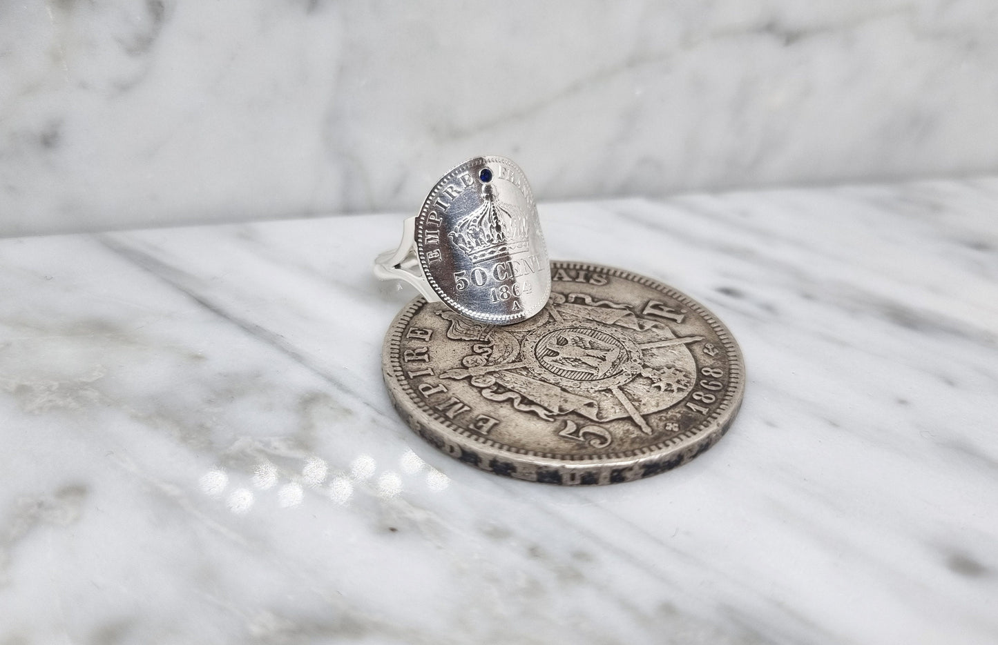 Bague pièce de monnaie 50 Centimes Napoléon III "Empire Français" cintrée en argent serti d'un saphir.